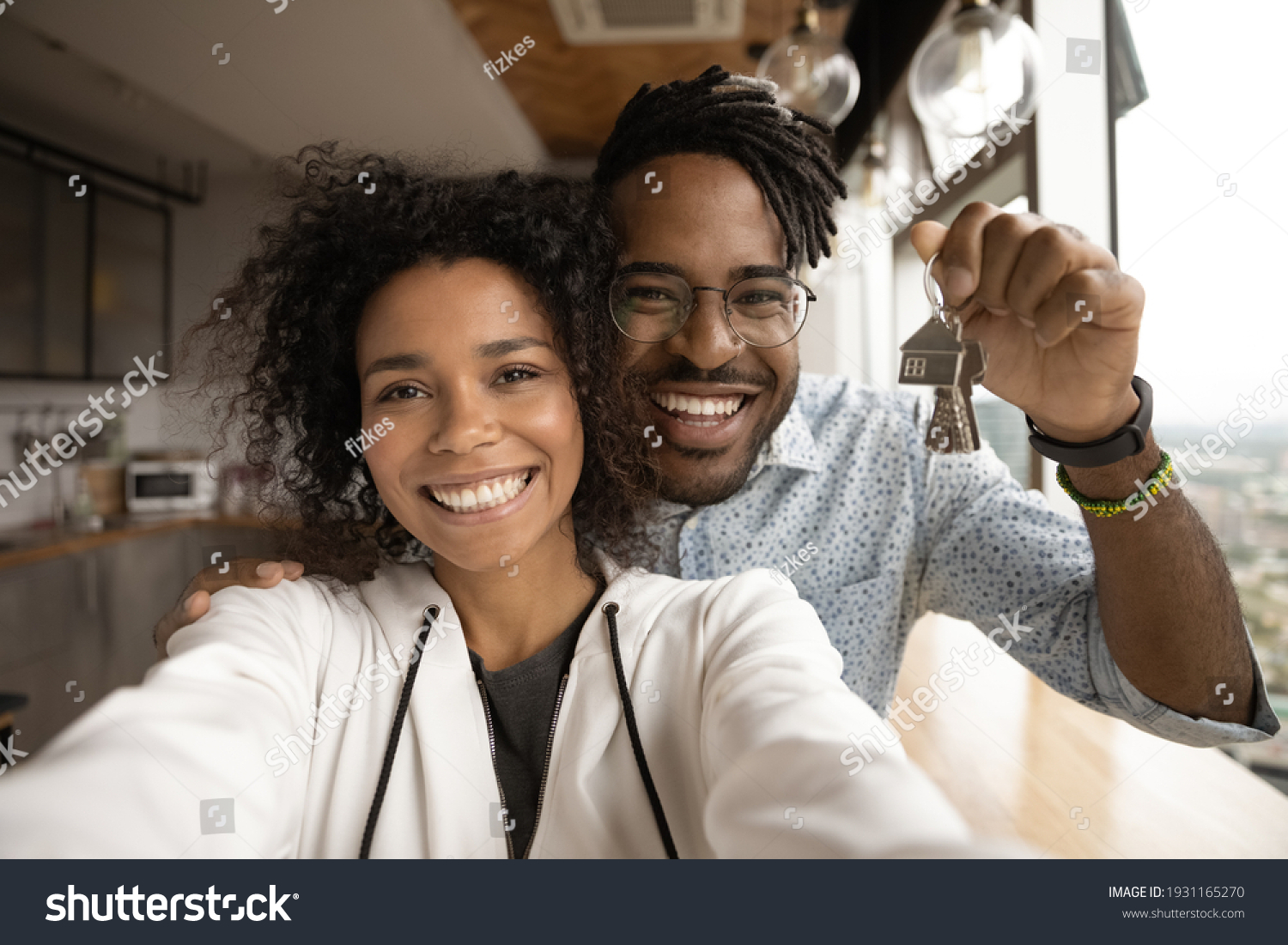 Head shot portrait overjoyed African American married couple showing keys, happy wife and husband, homeowners or tenants making selfie, purchased first dwelling, new apartment, mortgage concept #1931165270