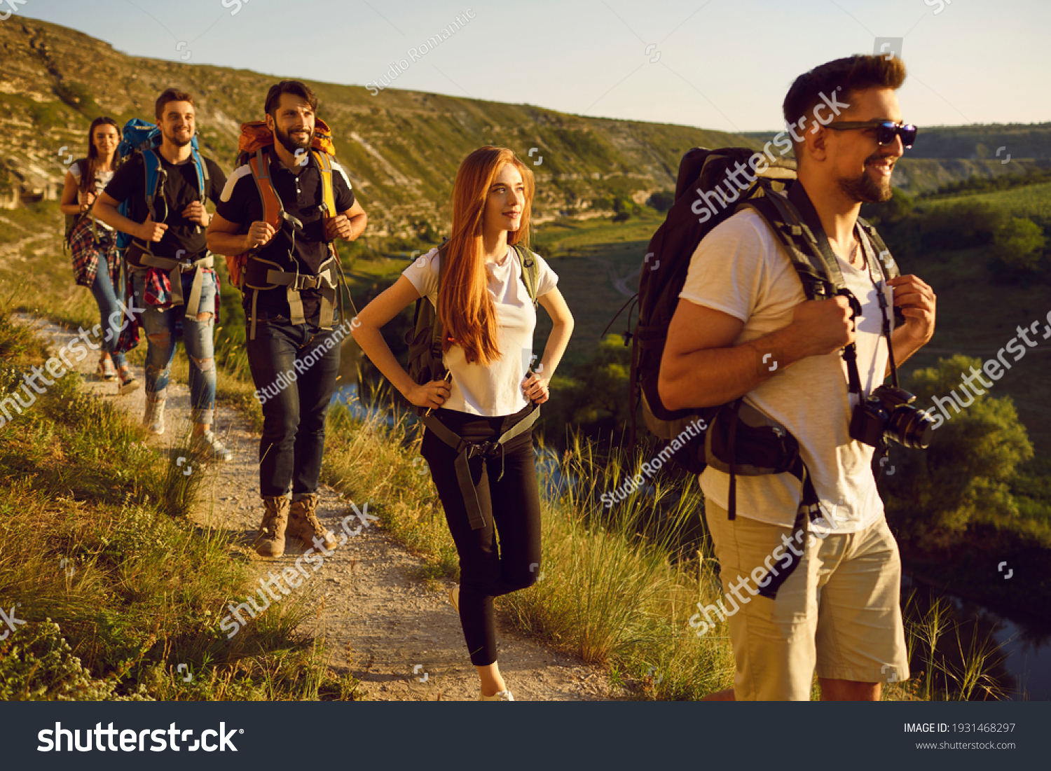 Group of men and women walk in a row along the trail during a walking tour of the mountains. Adventure, travel, tourism, hike and people concept. Camping season. #1931468297