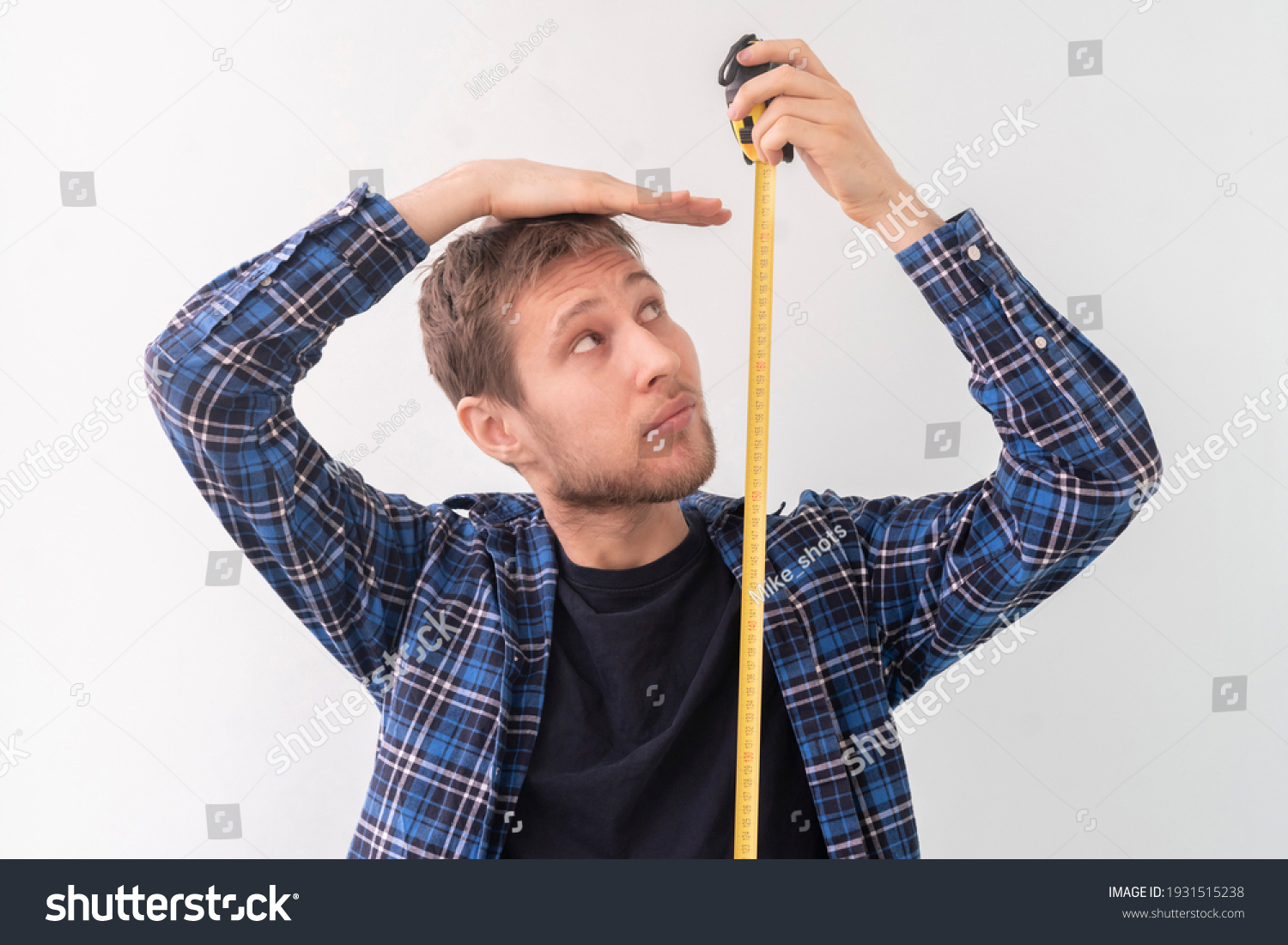 simple adult teenager male person with a roll tape measure the height against the wall #1931515238