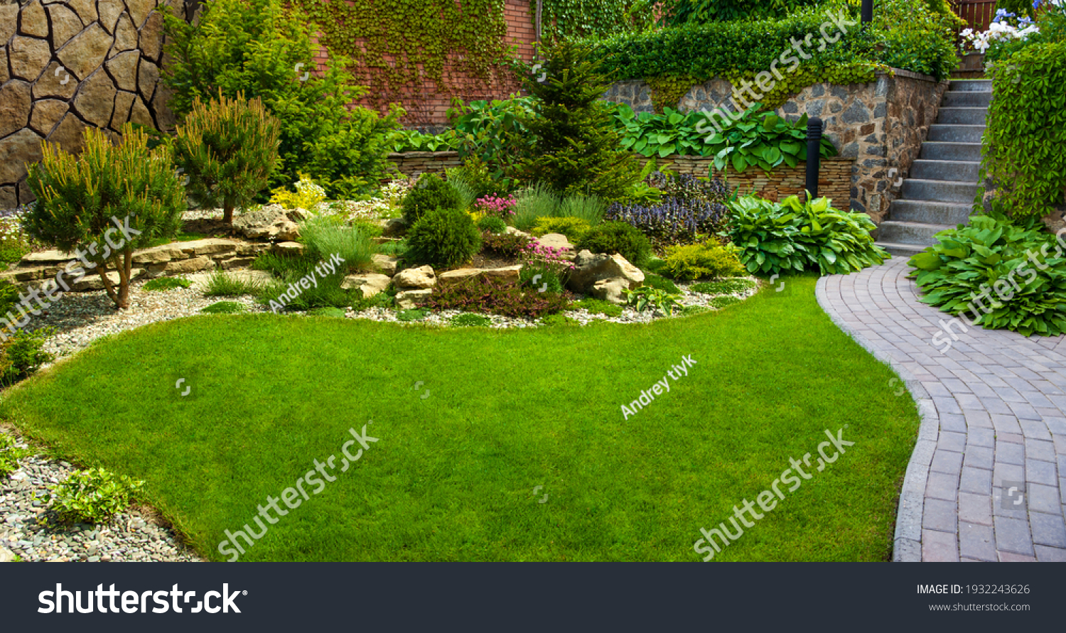 Garden stone path with grass growing up between the stones.Detail of a botanical garden. #1932243626
