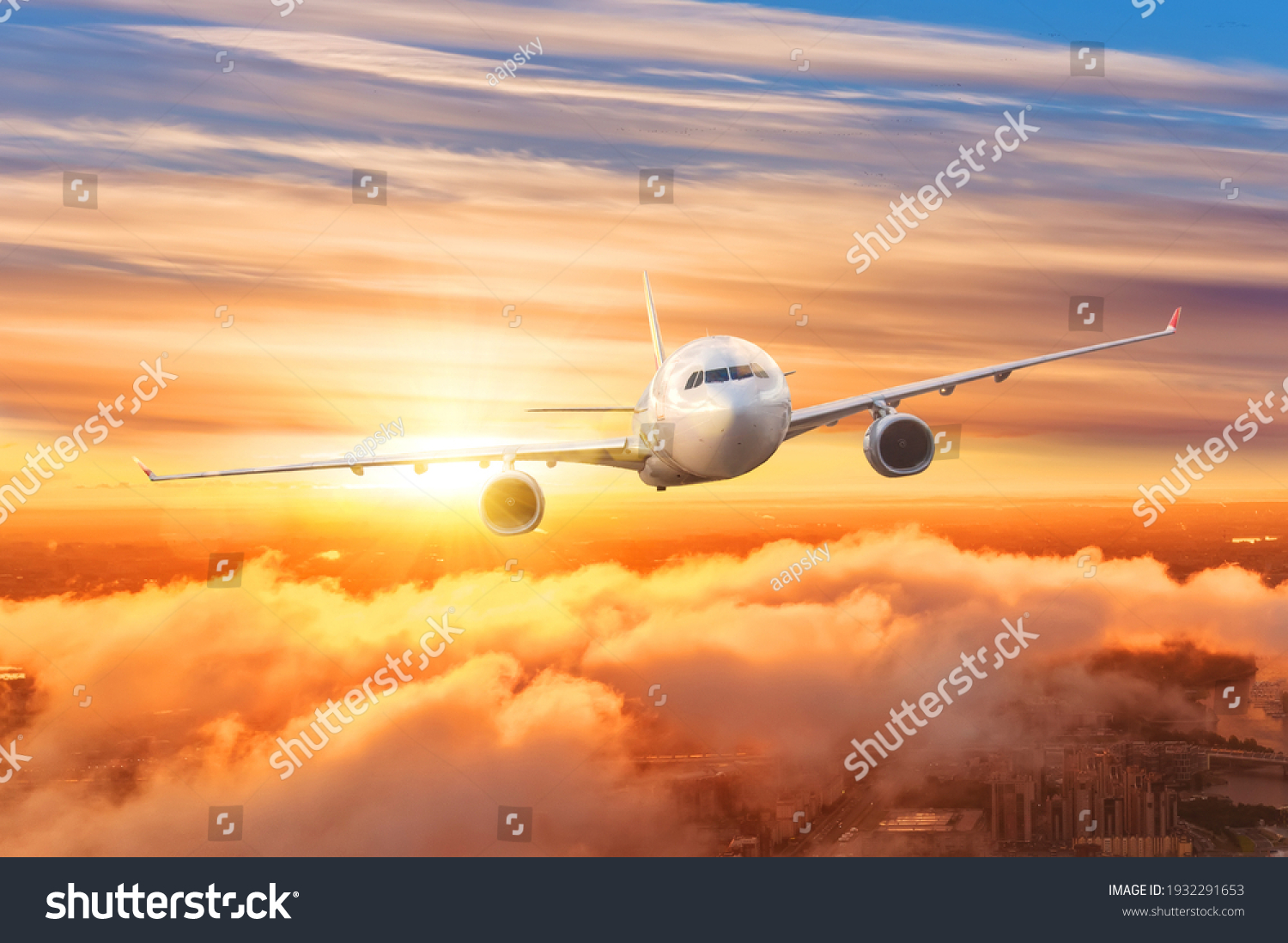 Airplane above the clouds in the sky at sunrise #1932291653