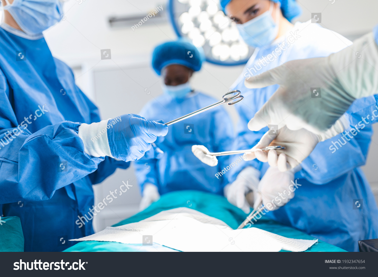 Low Angle Shot in the Operating Room, Assistant Hands out Instruments to Surgeons During Operation. Surgeons Perform Operation. Professional Medical Doctors Performing Surgery. #1932347654