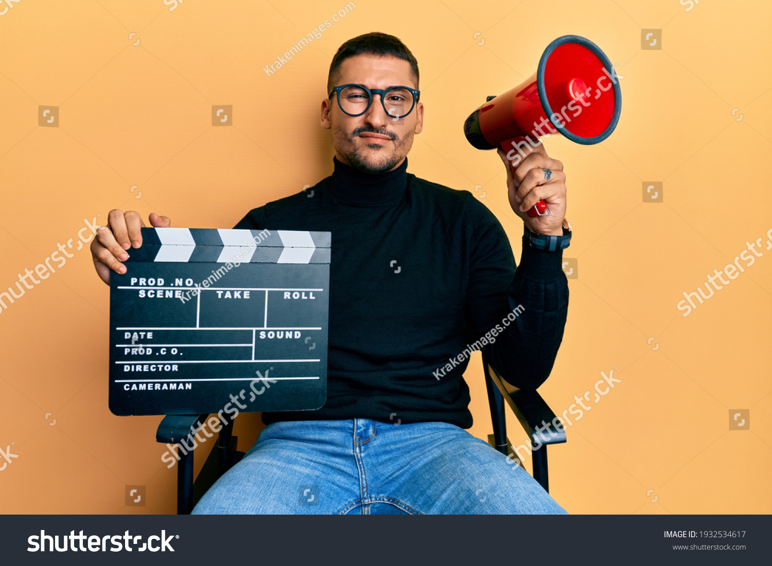 Handsome man with tattoos holding video film clapboard and megaphone skeptic and nervous, frowning upset because of problem. negative person.  #1932534617