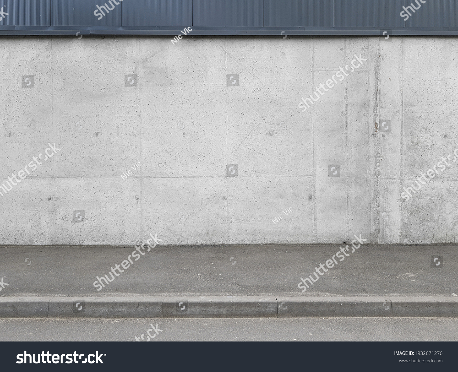 a fragment of an urban concrete wall of a building and an asphalt sidewalk, a building facade, a template or source #1932671276