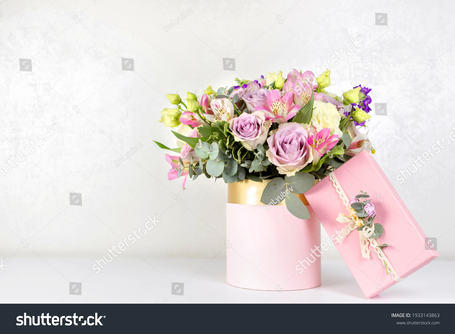 Beautiful bouquet of flowers in round box and pink gift box on a white table. Gift for holiday, birthday, Wedding, Mother's Day, Valentine's day, Women's Day. Floral arrangement in a hat box. #1933143863