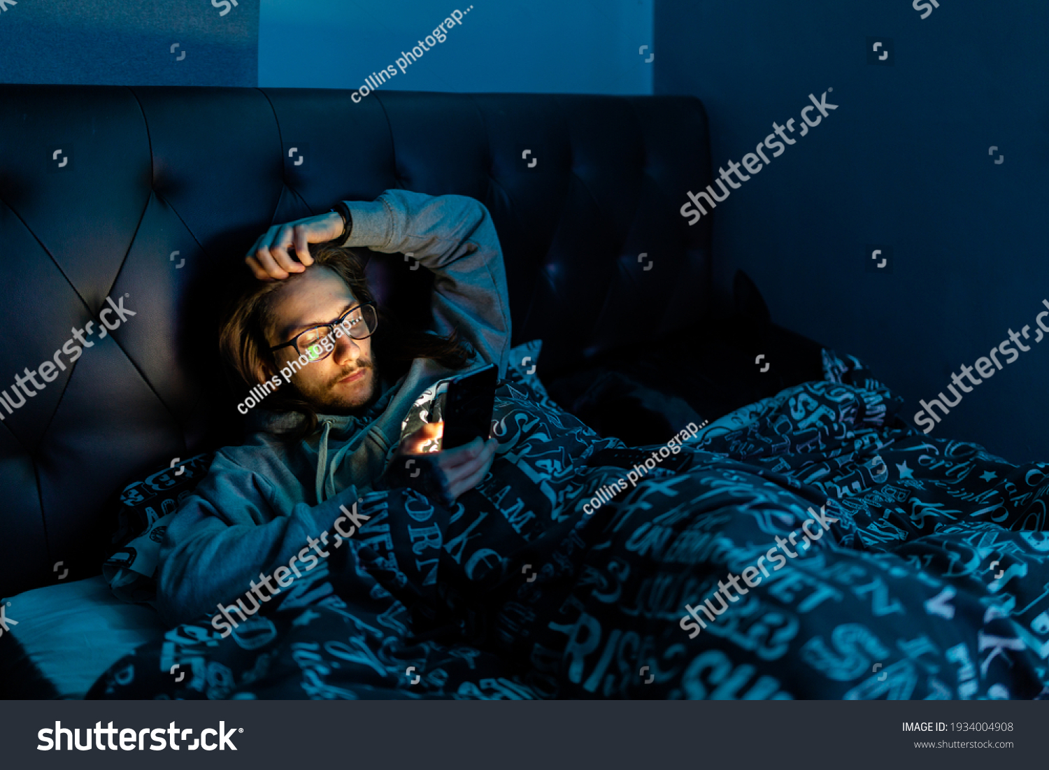 A young man addicted to social media checking his phone before going to bed, Addiction, social media, after dark concept #1934004908