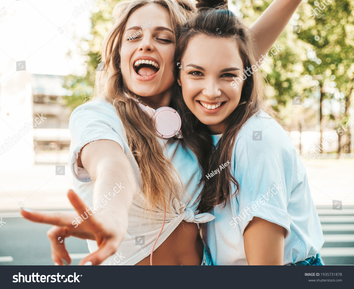 Portrait of two young beautiful smiling hipster female in trendy summer white t-shirt clothes.Sexy carefree women posing on street background. Positive models having fun, hugging and going crazy #1935731878
