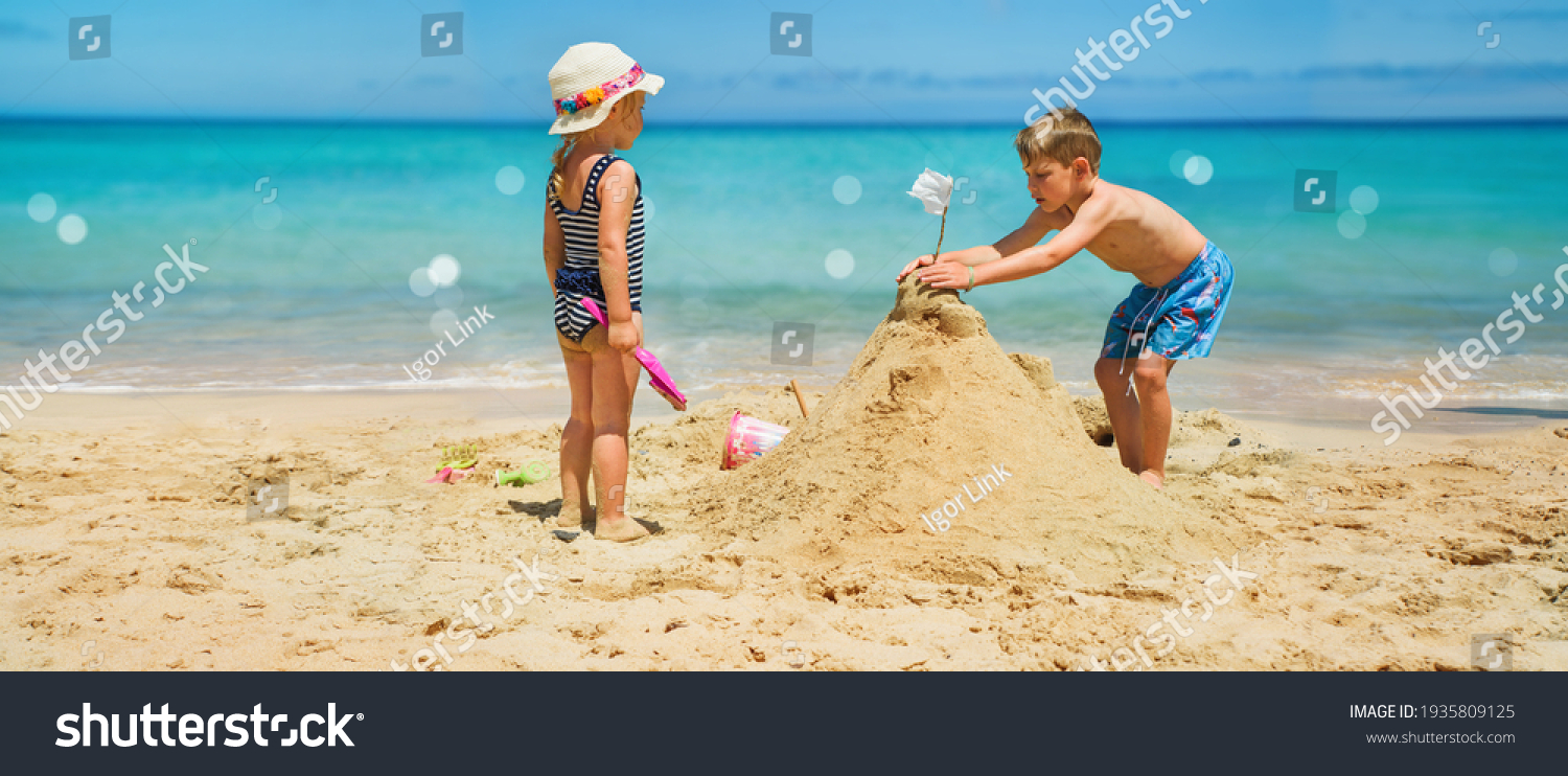 Sibling boy building a sandcastle at the beach in summer #1935809125