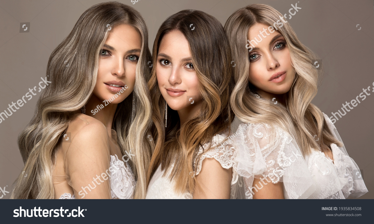 Three beautiful girls in  white wedding dresses  with hair coloring in ultra blond. Stylish hairstyle curls done in a beauty salon. Fashion, cosmetics and makeup.Adorable brides #1935834508