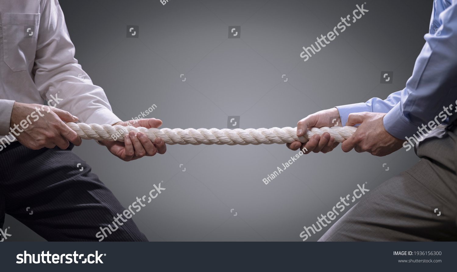 Two businessmen pulling tug of war with a rope concept for business competition, rivalry, challenge or dispute #1936156300