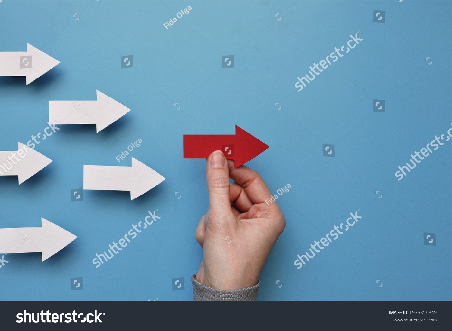 Many white arrows follow one red arrow. Symbol of following the leader straight to the goal #1936356349