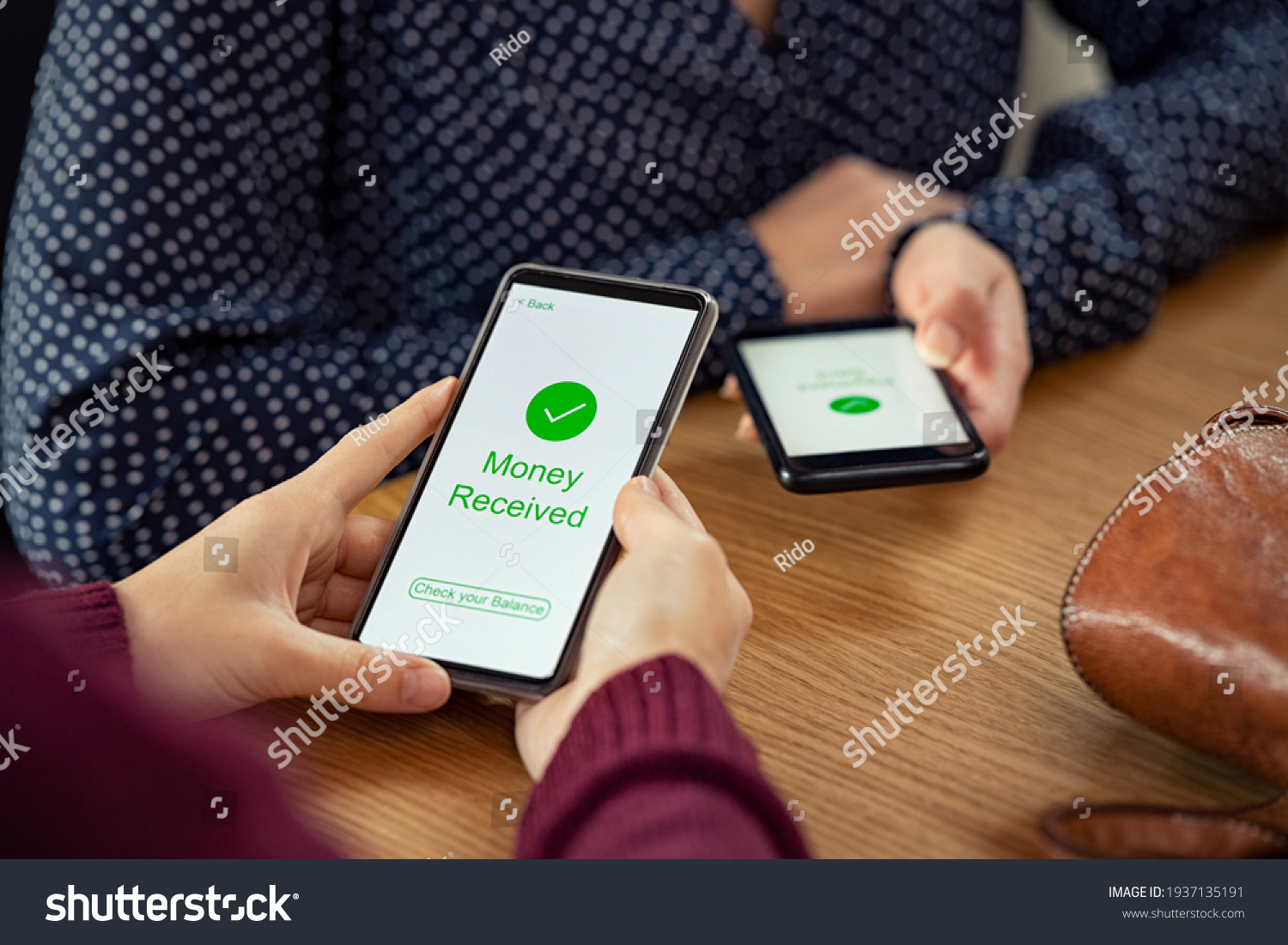 Close up of woman hands holding mobile phone with application to receive money. People holding smart phone and making cashless payment transaction. Smartphone screen displaying money received message. #1937135191