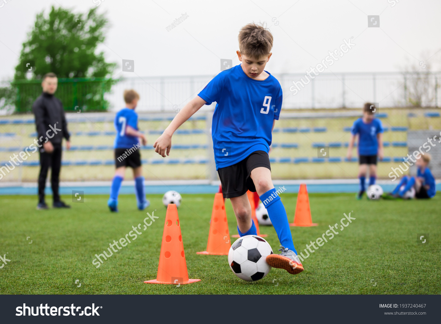 Boys attending soccer training on school field. Young man coaching children on physical education class. Soccer practice for children #1937240467
