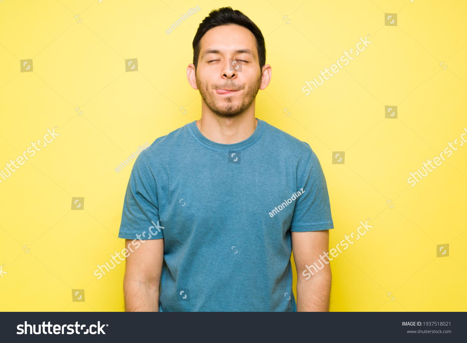 Cheerful man thinking about eating a delicious lunch with his eyes closed. Handsome man in his 30s licking his lips and craving a tasty dinner #1937518021