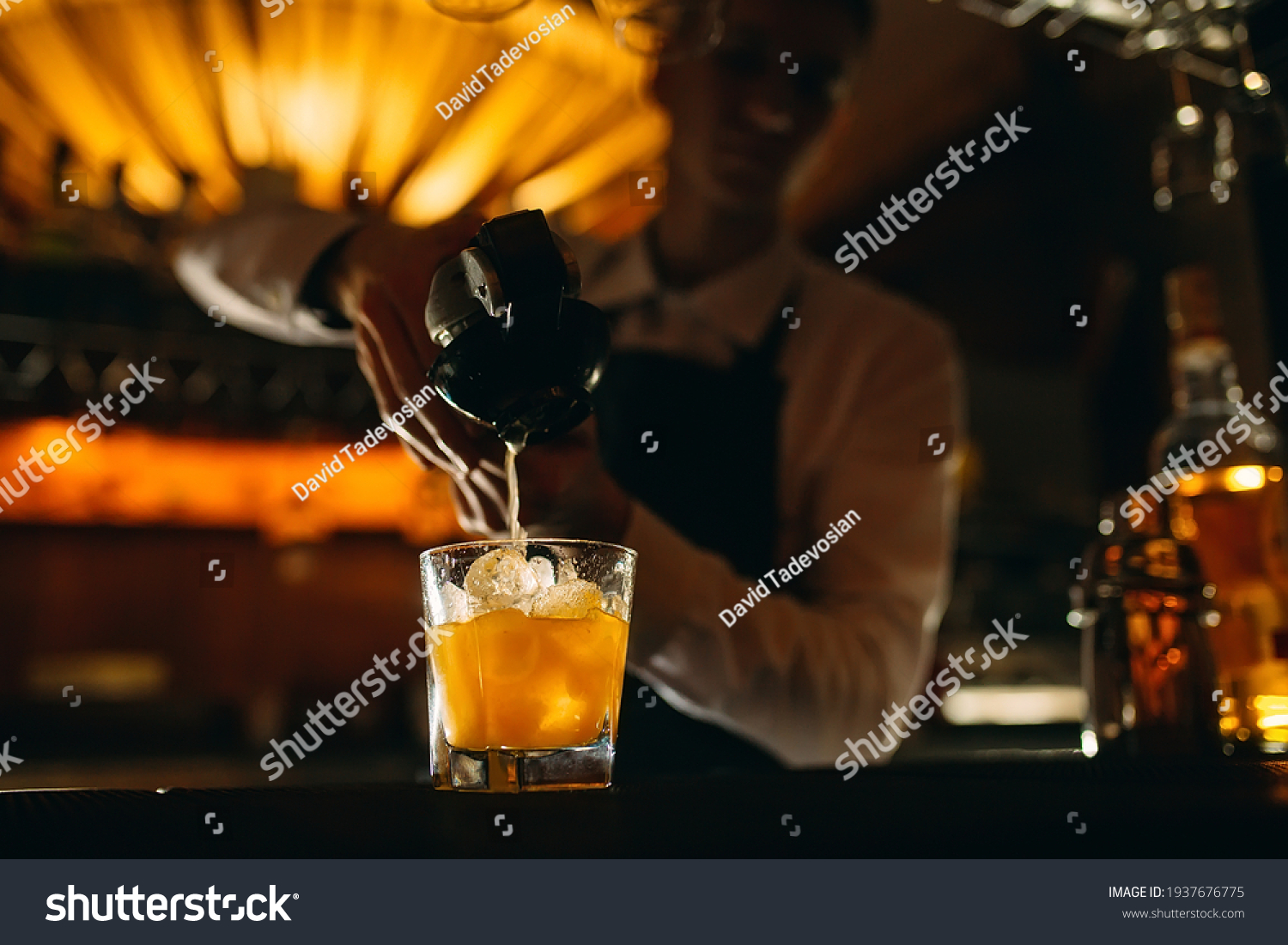 The bartender squeezes citrus juice into a cocktail #1937676775