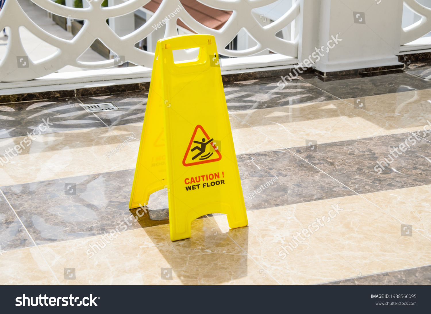 Yellow warning sign Caution Wet Floor on a marble floor in a public area. Preventing injuries to hotel guests during wet cleaning of halls and public places. #1938566095