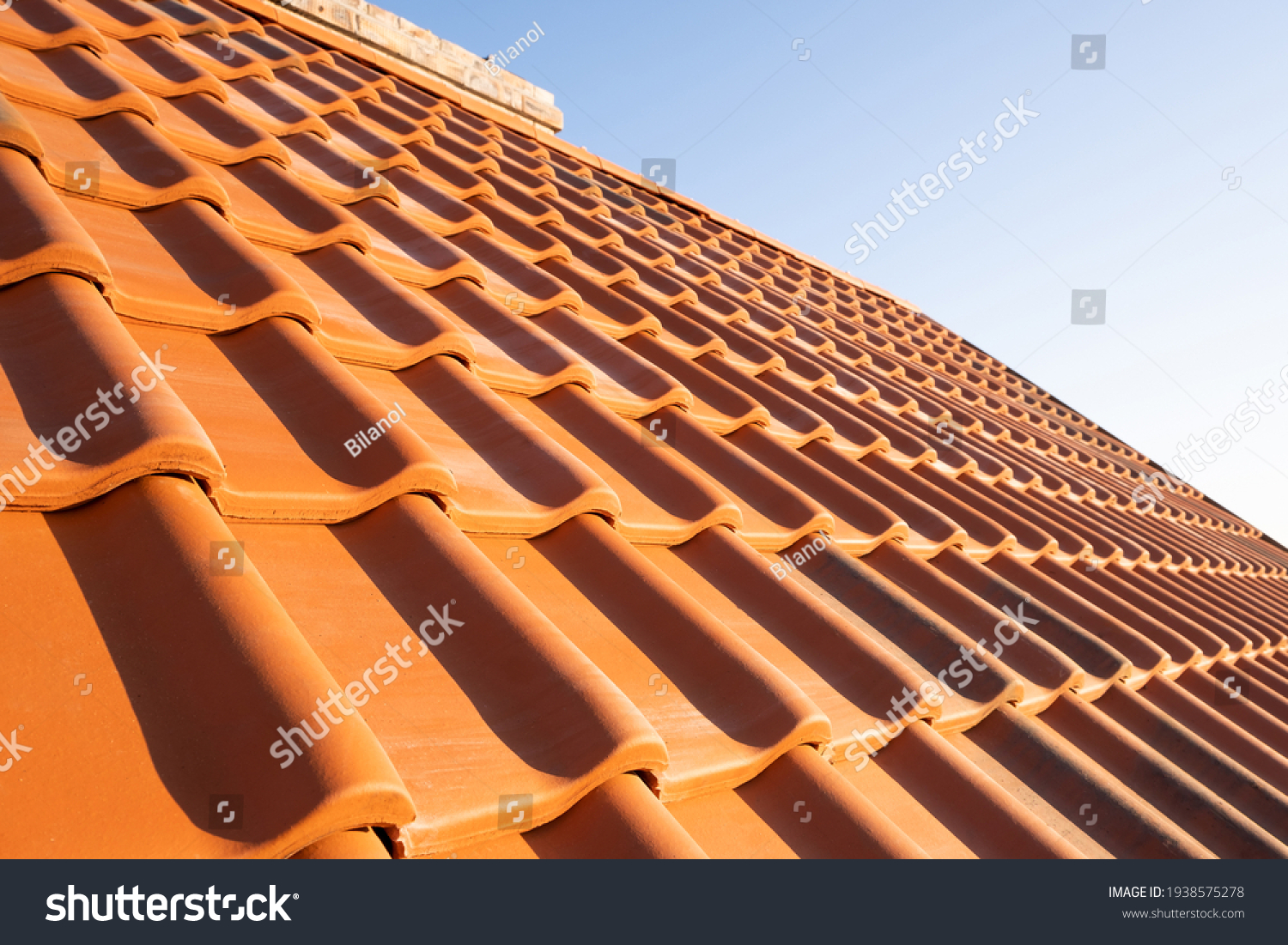 Overlapping rows of yellow ceramic roofing tiles covering residential building roof. #1938575278