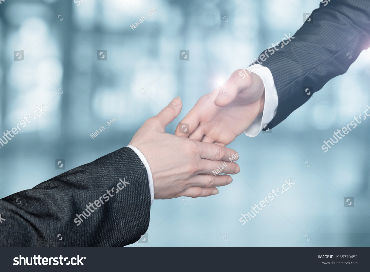 Businessmen reach out to each other to shake hands on a blurred background. #1938770452