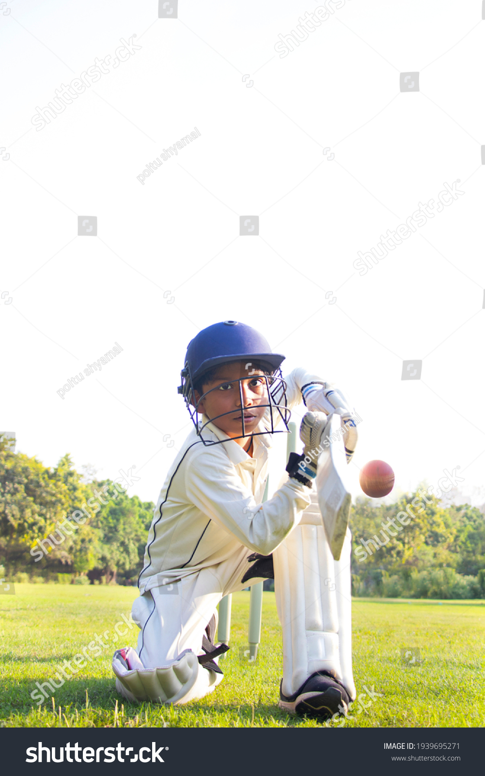 Young boy batting in protective gear during a cricket #1939695271