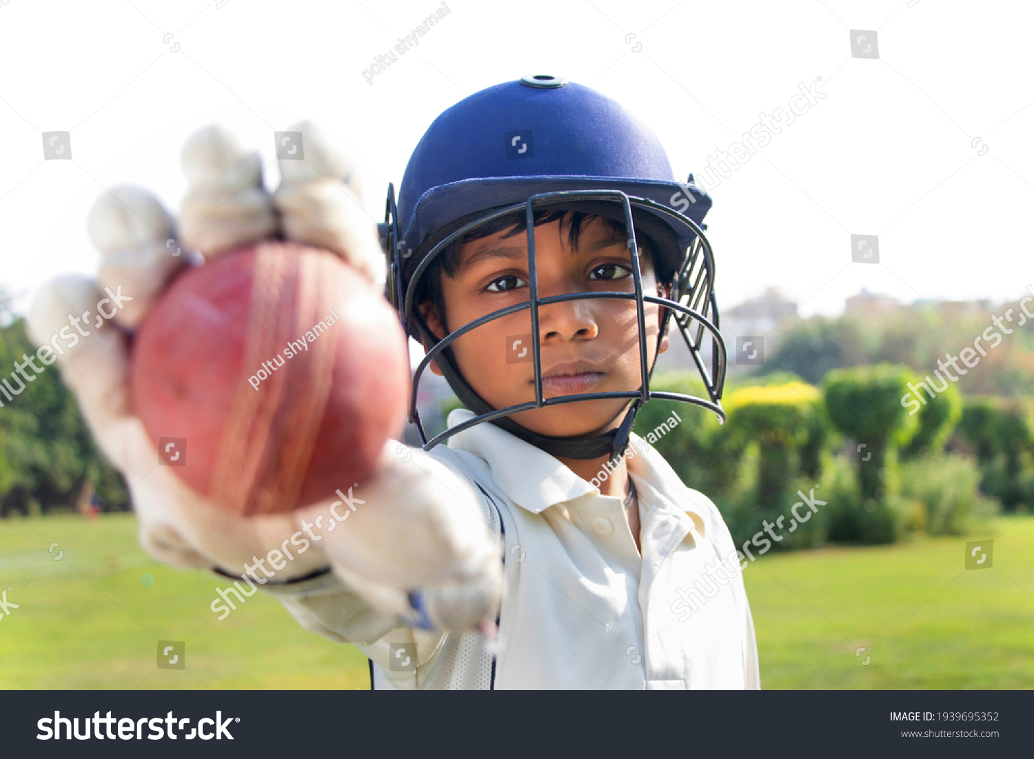 Portrait of boy wearing cricket helmet and Showing cricket ball #1939695352