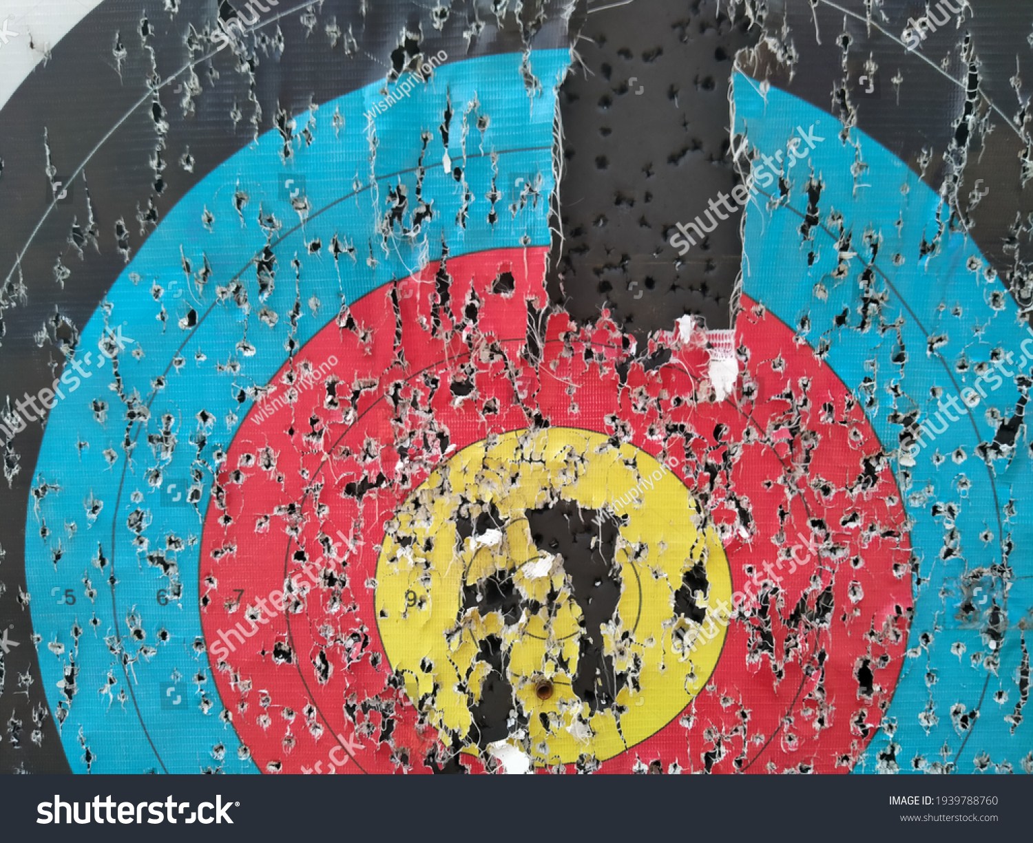 Archery target close up with many arrow holes in Gold, red, blue and black  #1939788760
