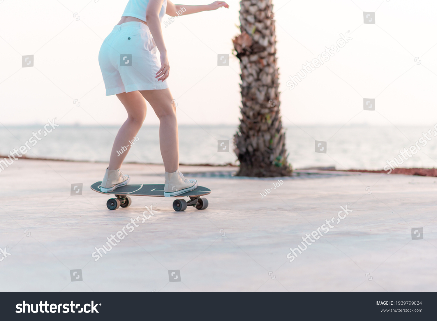 Close up rear view Asian women leg on surf skate or skate board in breach background #1939799824