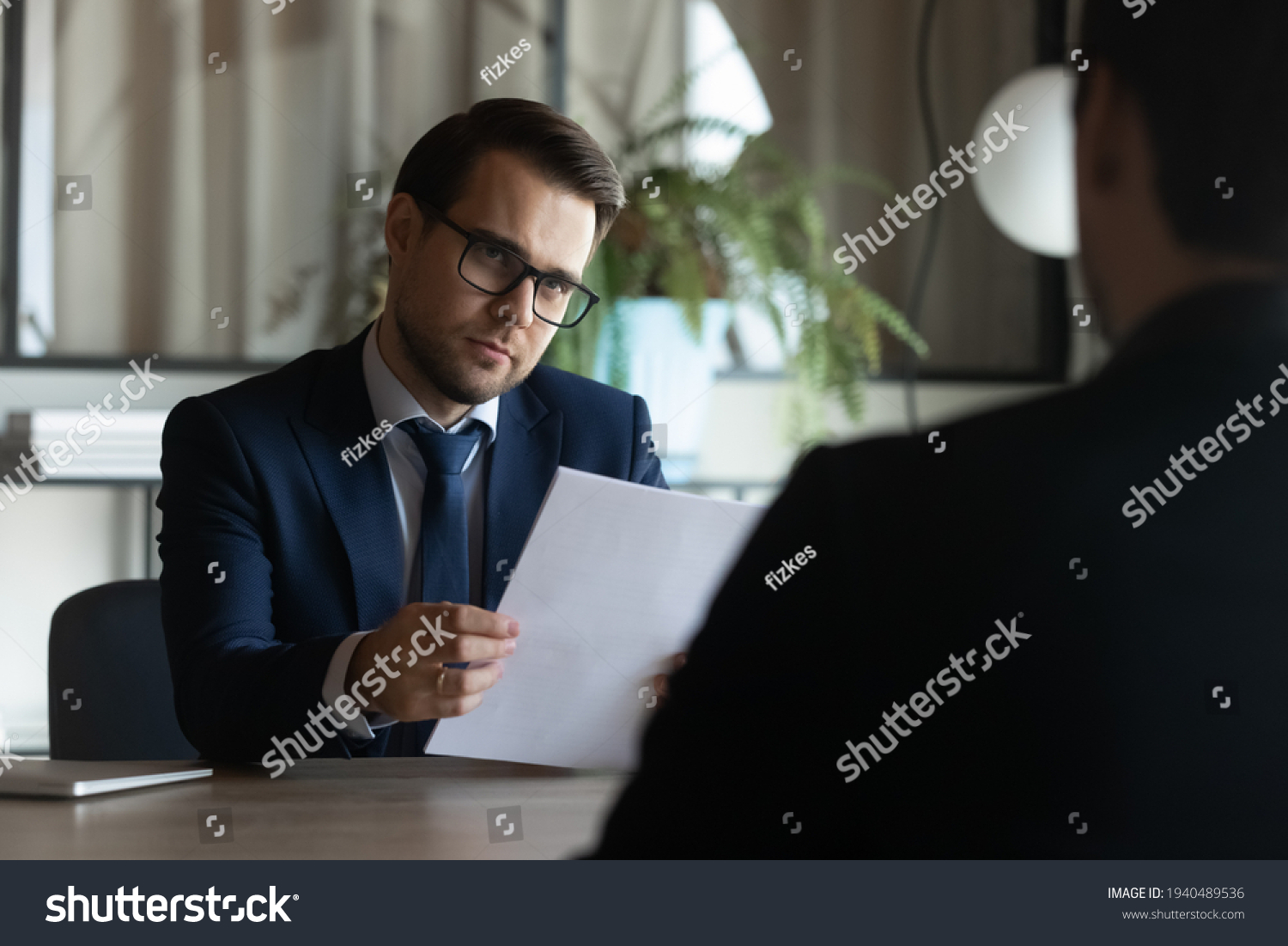 Young Caucasian businessman listen to male job applicant candidate at interview in office. Business partners or clients consider collaboration partnership at briefing. Cooperation, employment concept. #1940489536