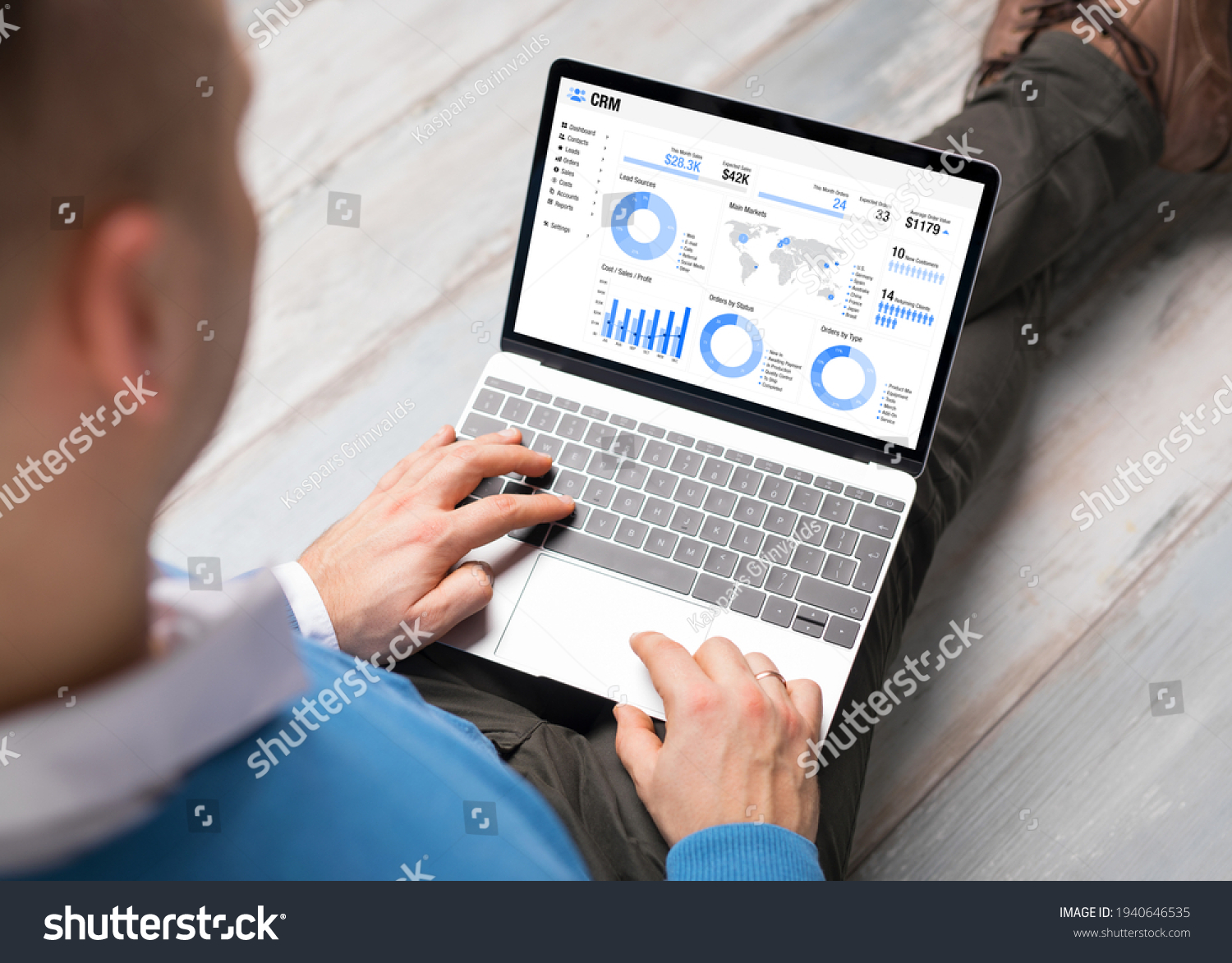 Man using CRM software on laptop with different graphs and charts showing sales data for his business #1940646535