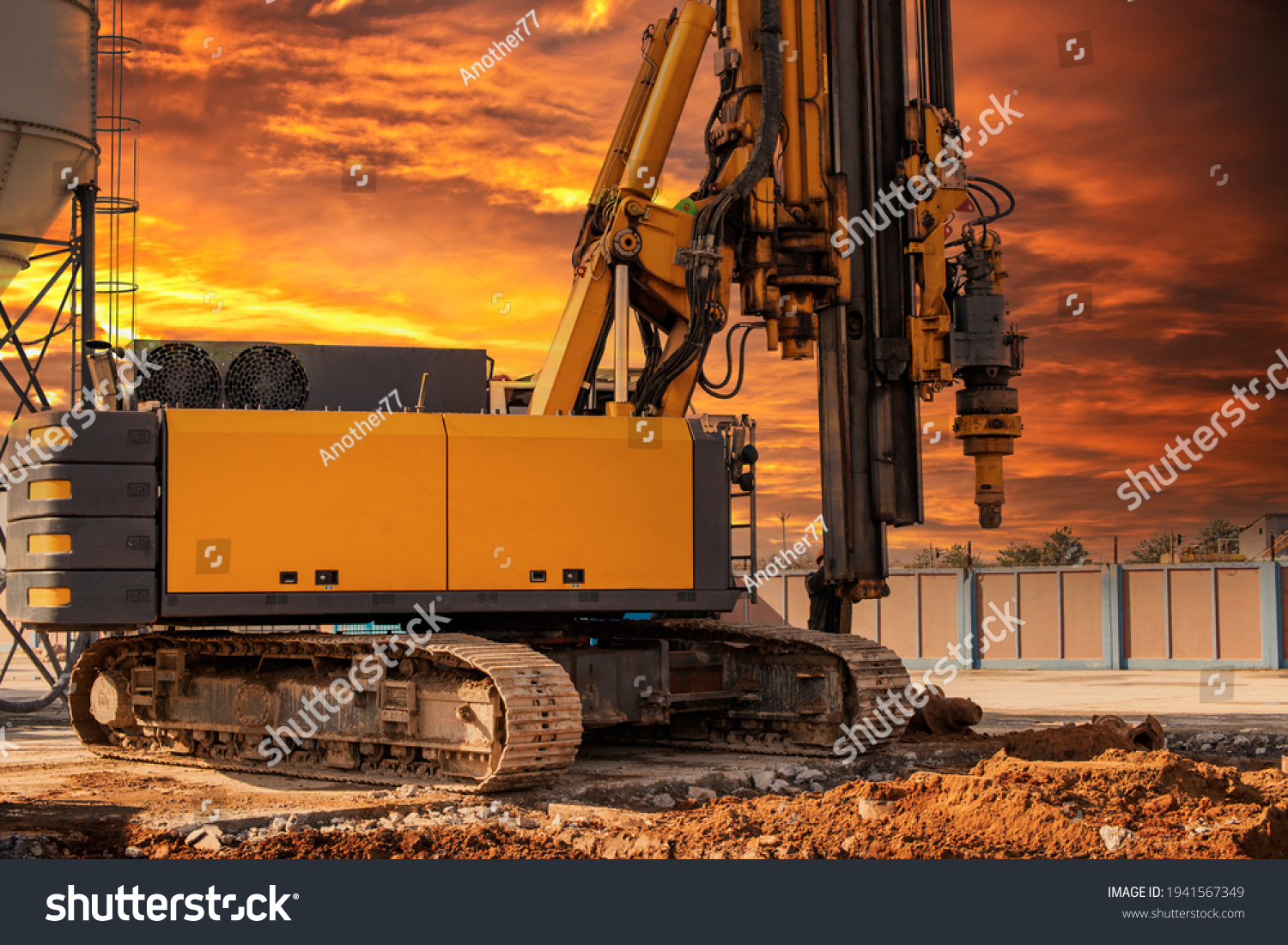 Hydraulic drilling rig against the backdrop of the sunset sky. Installation of bored piles by drilling. Foundations and foundations. Drilling in the ground #1941567349