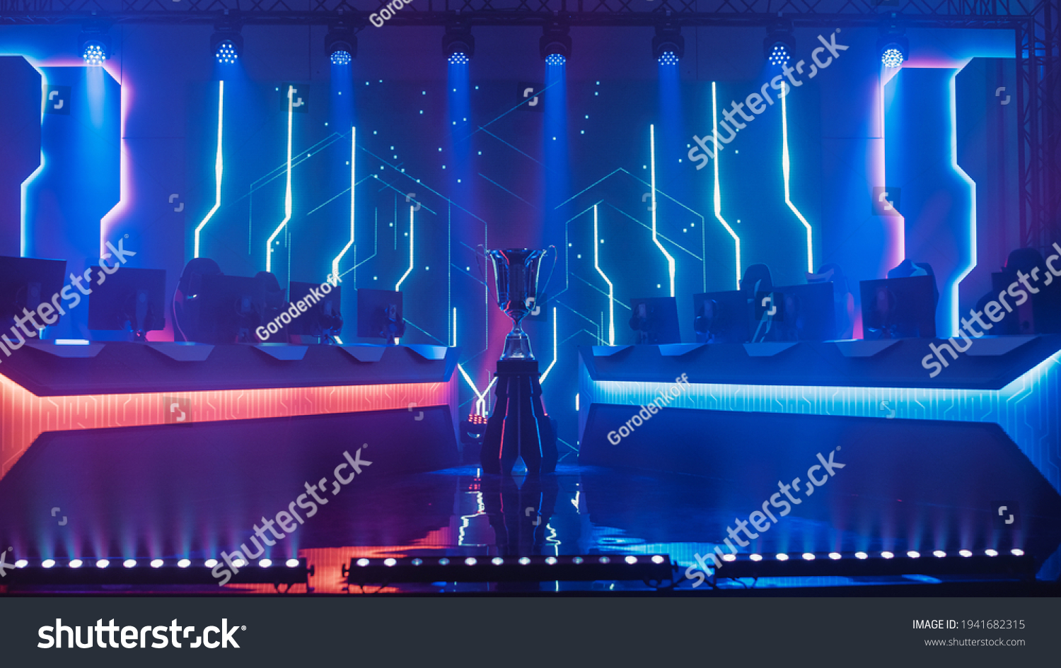 eSports Winner Trophy Standing on a Stage in the Middle of the Computer Video Games Championship Arena. Two Rows of PC for Competing Teams. Stylish Neon Lights with Cool Design. #1941682315