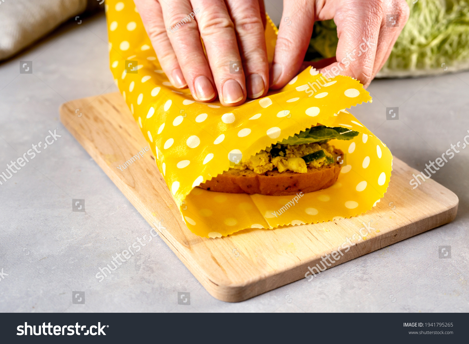 Woman hands wrapping a healthy sandwich in beeswax food wrap and cotton bag #1941795265