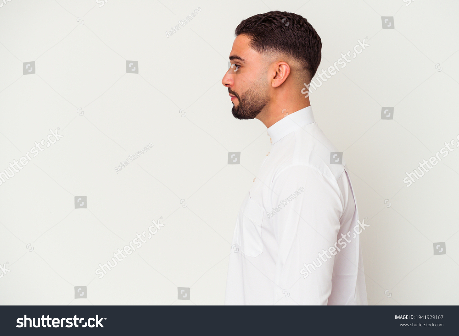 Young arab man wearing typical arab clothes isolated on white background gazing left, sideways pose. #1941929167