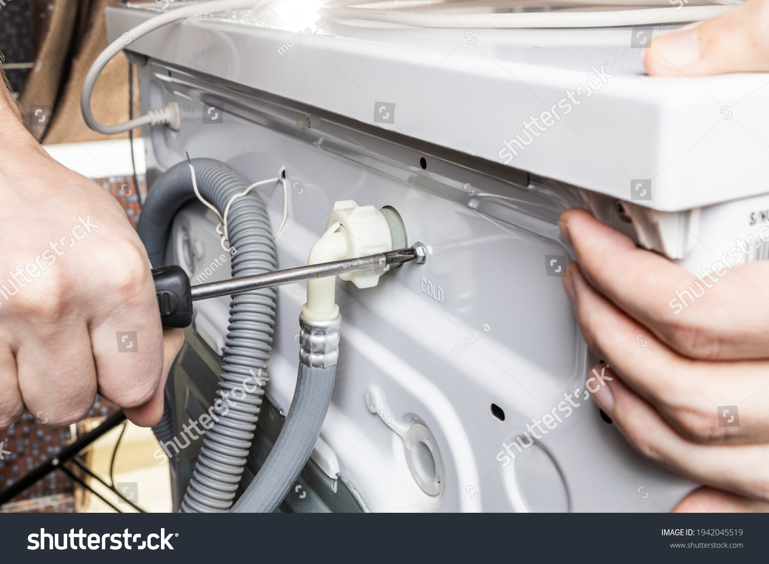 handyman repair washer at back side. washing machine repair service concept. connecting water supply to appliance. #1942045519