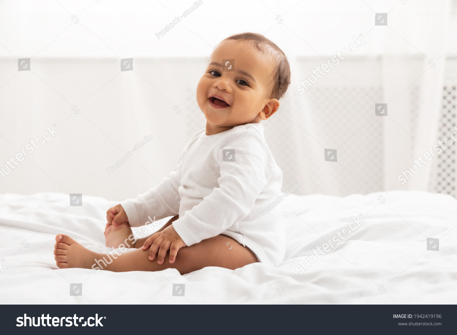 Portrait Of African Baby Toddler Smiling Sitting On Bed Indoor #1942419196