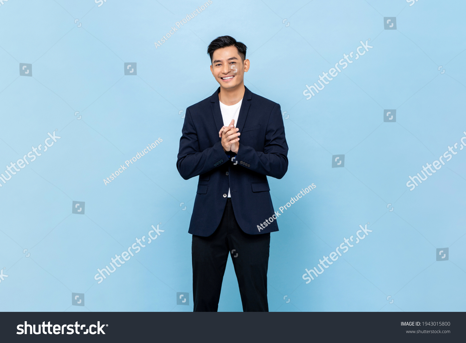 Smiling young handsome southeast Asian man clapping hands impressively in light blue studio isolated background #1943015800