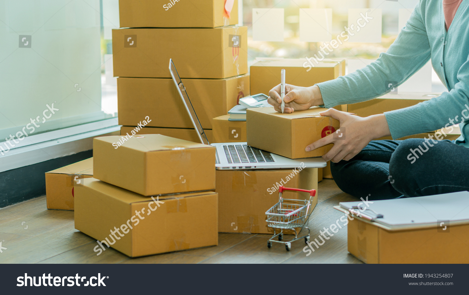 Startup Entrepreneurship Small Business SME Freelance Young lady working at home with boxes on the floor and laptop online Marketing Packaging SME Shipping Ecommerce Concepts #1943254807