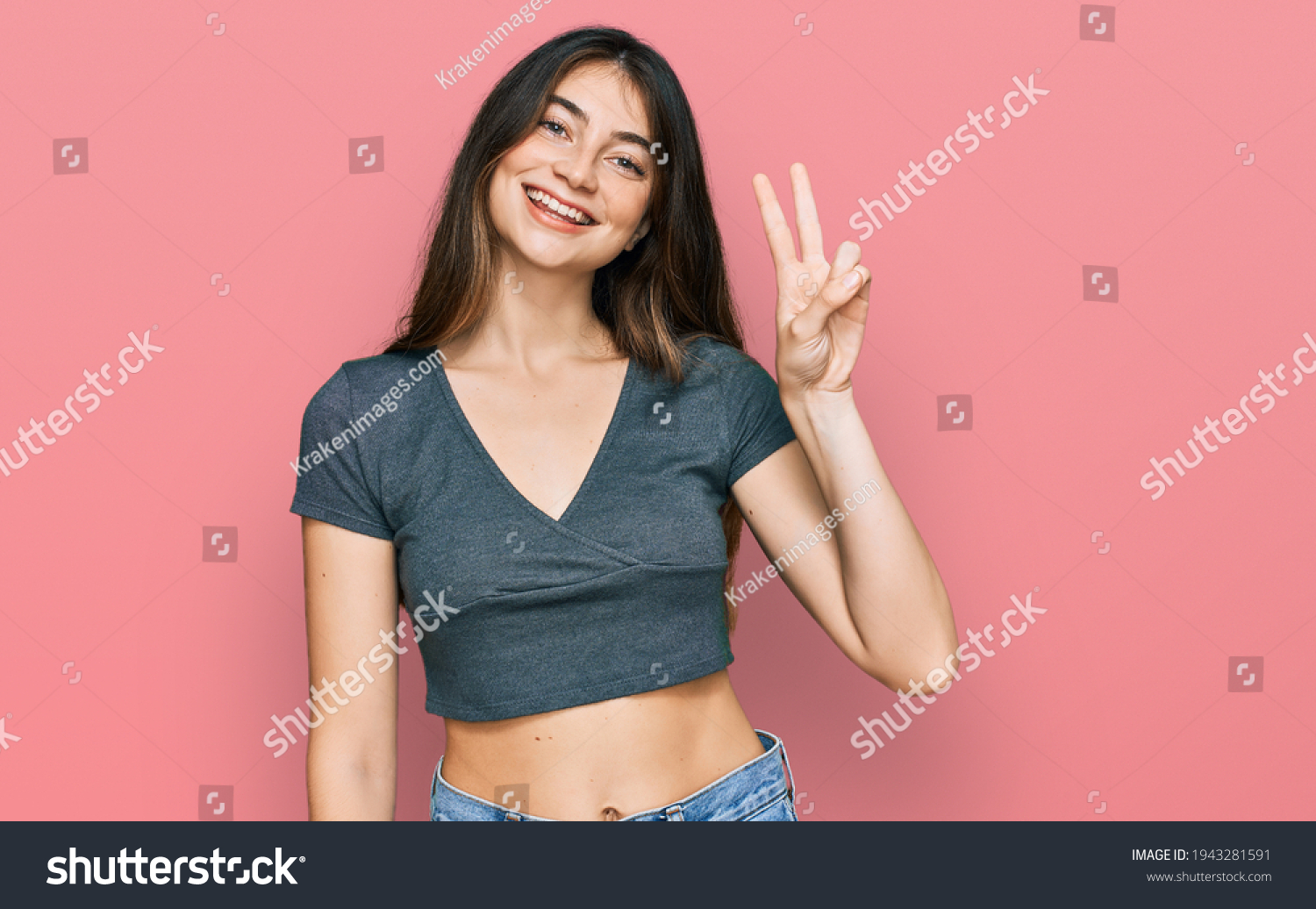 Young beautiful teen girl wearing casual crop top t shirt showing and pointing up with fingers number two while smiling confident and happy.  #1943281591