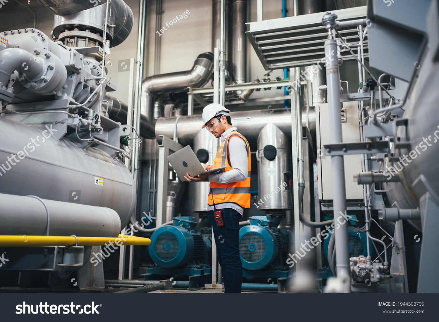 Professional worker of modern factory using laptop controlling program to automatic machinery. Engineering with laptop Programmable Logic Controller to manage large machine working full automatic. #1944508705
