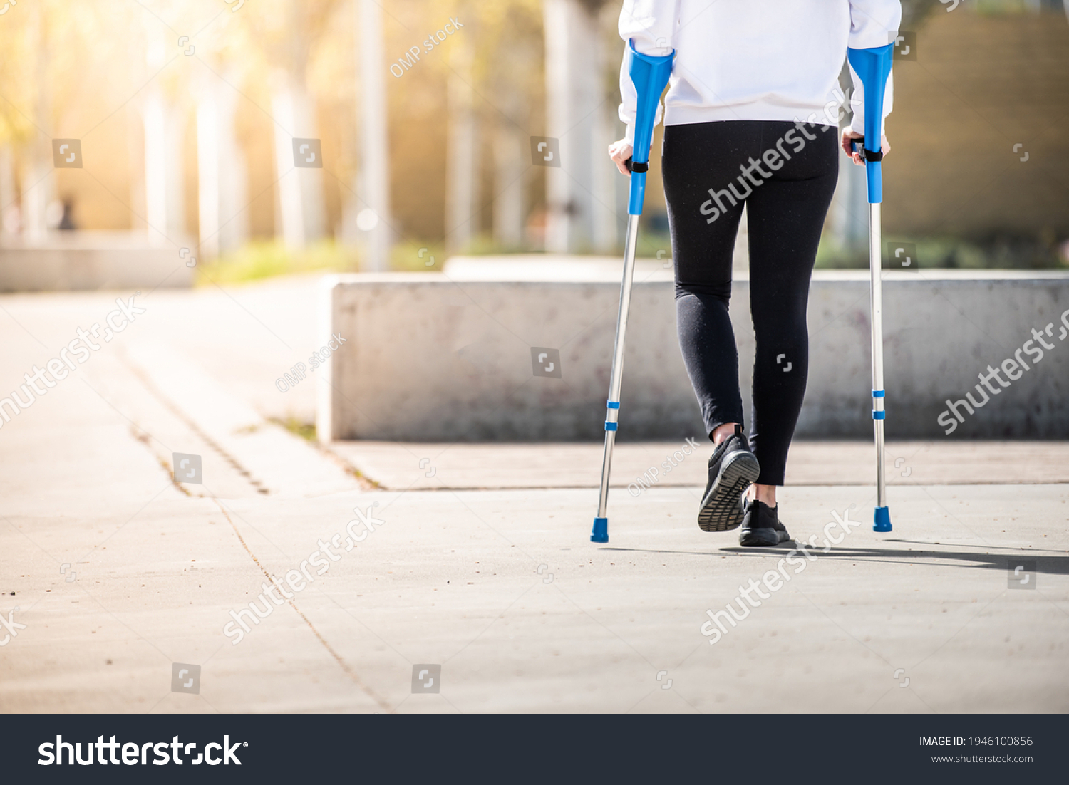 Girl from back with crutches, walking alone. Woman with crutches. Crutches #1946100856