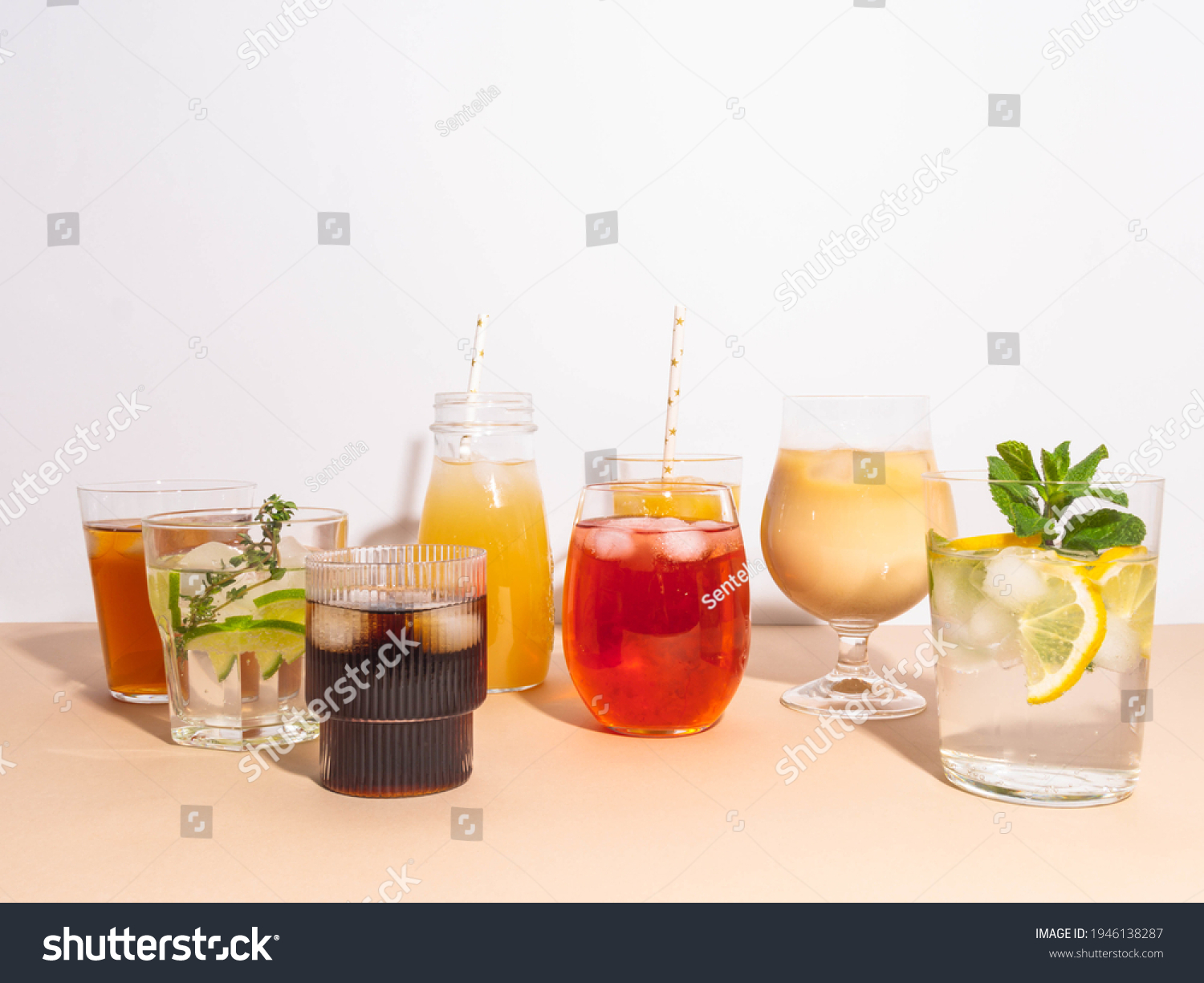 Various refreshing non-alcoholic drinks in glasses with ice. Different juice, homemade lemonade, iced coffee, iced fruit tea and smoothies on beige background. Copy space. Front view #1946138287