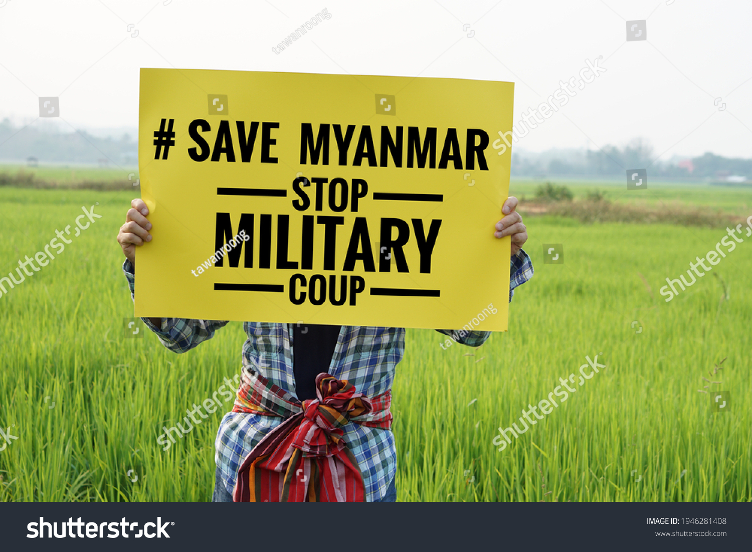 Text "#Save Myanmar stop military coup" on paper sign hold by a man at green paddy field. Concept protesting for democracy and against the coup in Myanmar. #1946281408