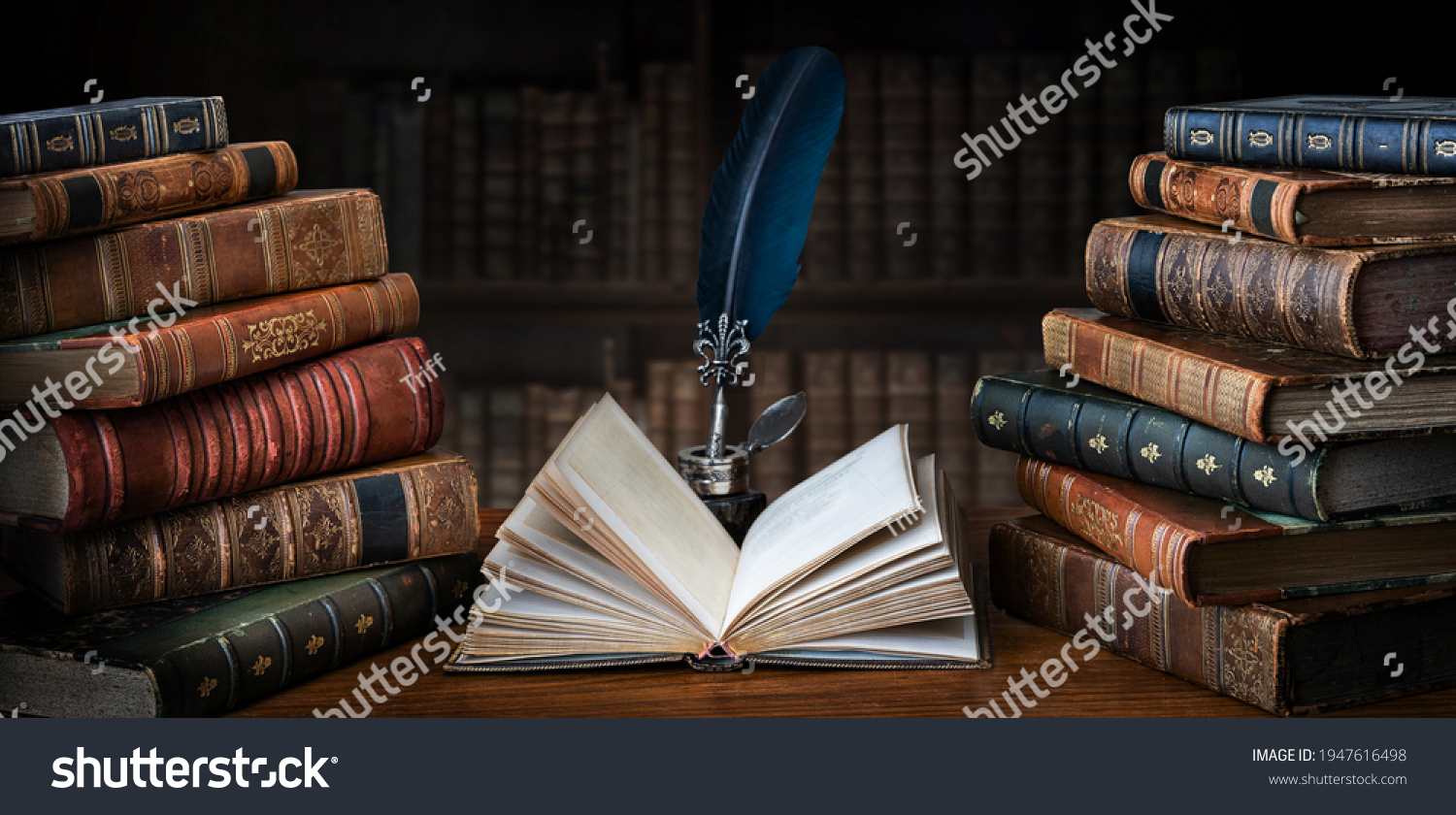 Old books ,quill pen and vintage inkwell on wooden desk in old library. Ancient books historical background. Retro style. Conceptual background on history, education, literature topics. #1947616498