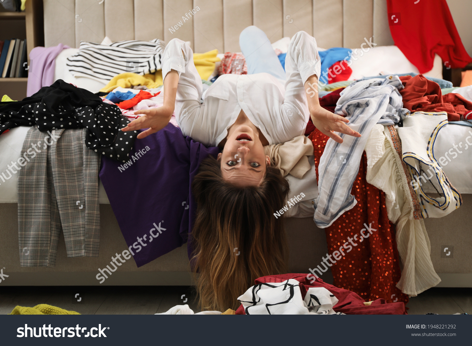 Young woman surrounded by different clothes in messy room. Fast fashion concept #1948221292