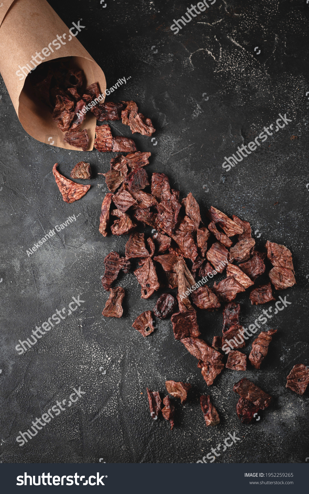 Dog treats. Dried pieces of lung on a dark stone background. Helpful treats for pets. Flatlay, space for text. Jerky #1952259265