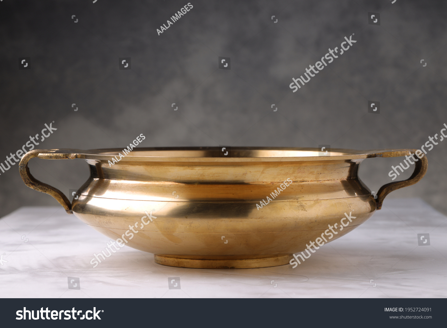 Urule or Brass vessel,an empty traditional  south Indian cooking vessel which is very shiny placed on grey textured background. #1952724091