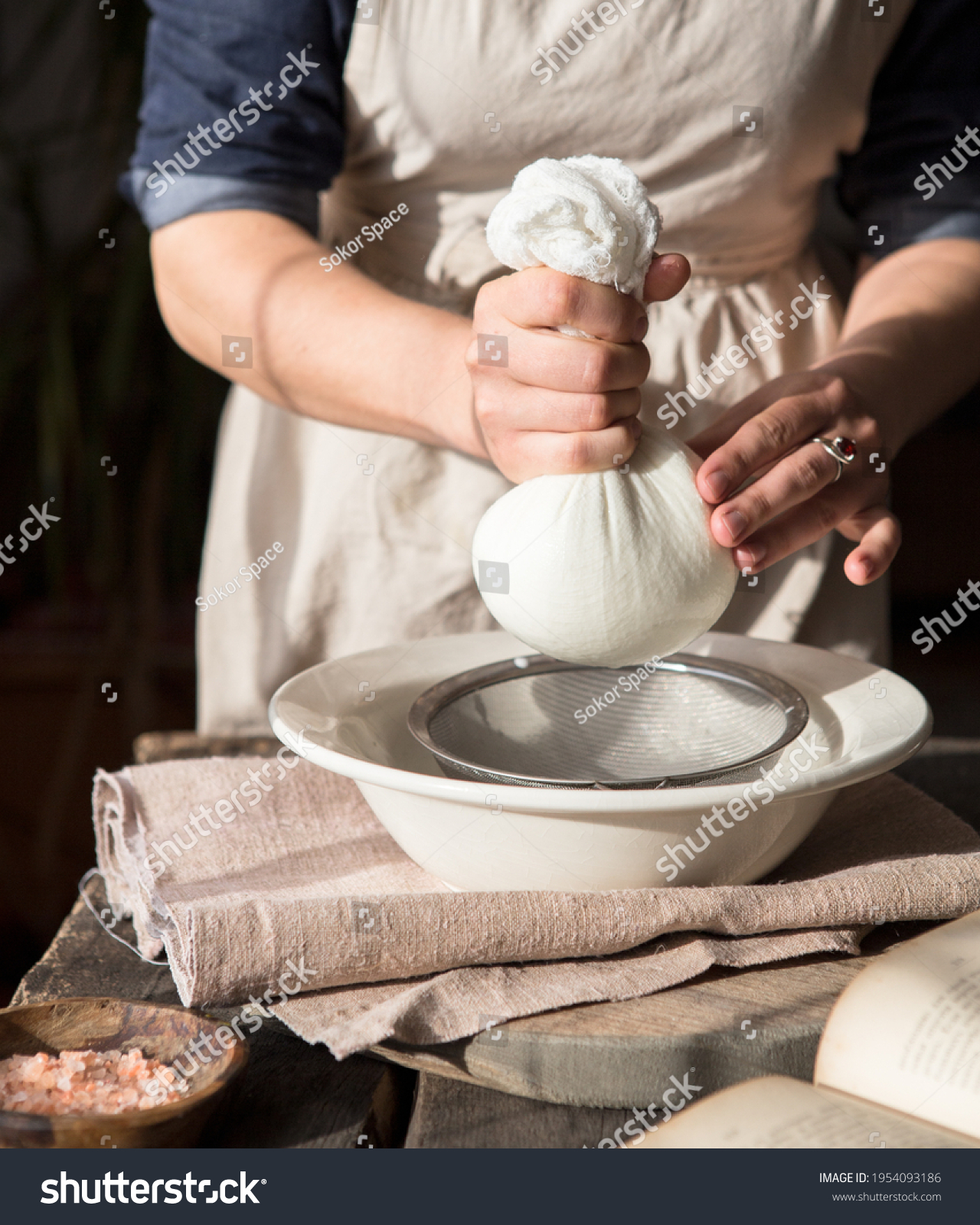 Preparation of almond milk - woman straining the milk through a cheesecloth #1954093186