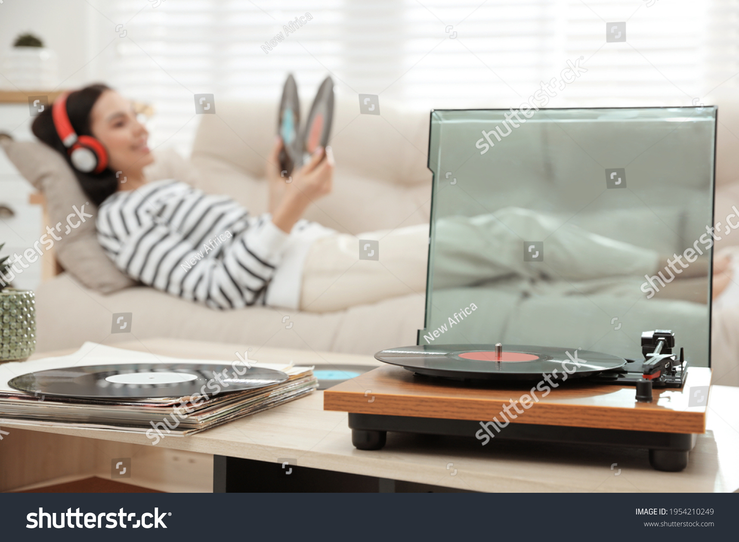 Woman listening to music with turntable in living room #1954210249
