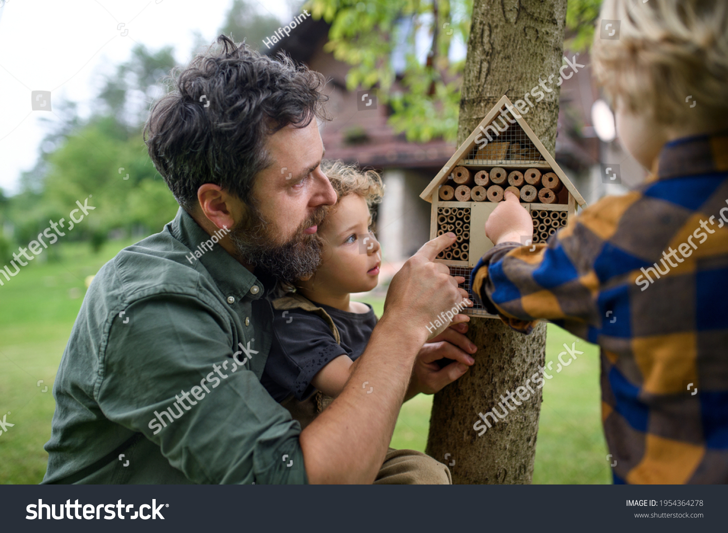 Small children with father holding bug and insect hotel in garden, sustainable lifestyle. #1954364278