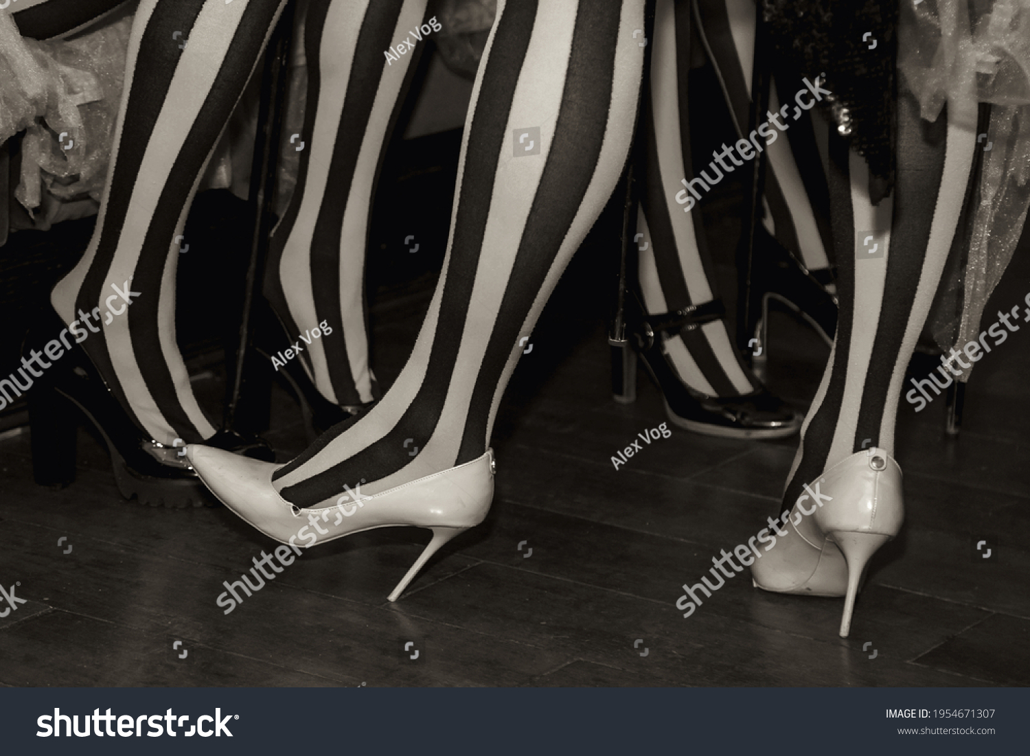 Close-up of legs of circus performer in suit and striped red-black stockings in dressing room. Circus performer waiting for an invitation to enter stage or arena. Concert performance for backgrounds #1954671307