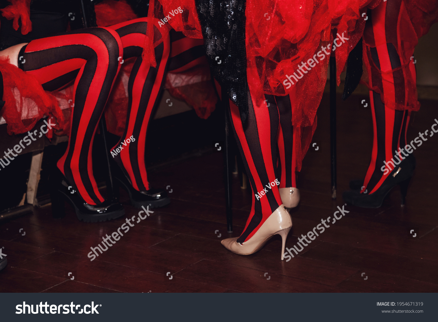 Close-up of legs of circus performer in suit and striped red-black stockings in dressing room. Circus performer waiting for an invitation to enter stage or arena. Concert performance for backgrounds #1954671319